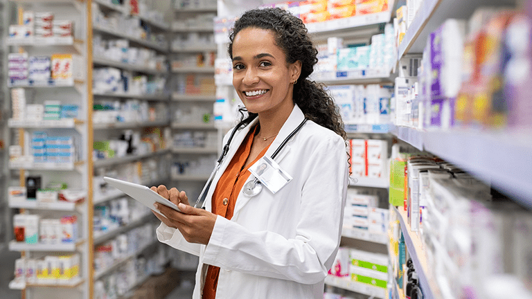 Portrait of a female pharmacist working in a pharmacy and holding a clipboard.