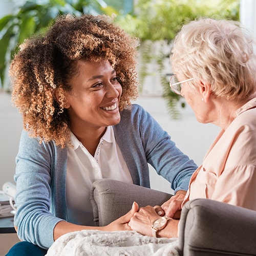 Female caregiver talking with senior woman, sitting and listening to her carefully.