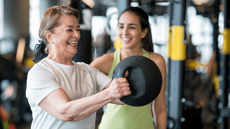 Adult woman exercising at the gym with a personal trainer