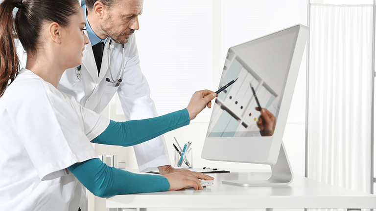 Two physician assistants review records on a computer.