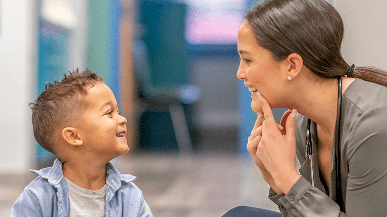 A speech therapist teaches a young boy how to sound out words.