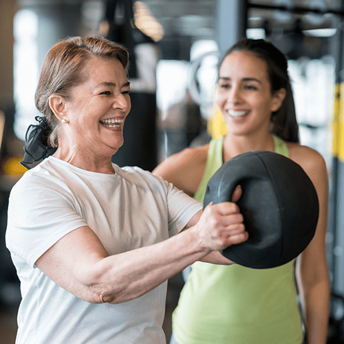 Adult woman exercising at the gym with a personal trainer