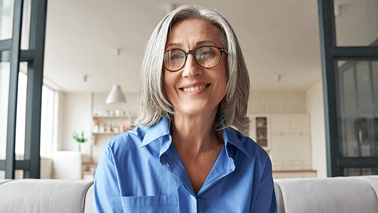 Smiling  woman looking at web camera during telehealth appointment.