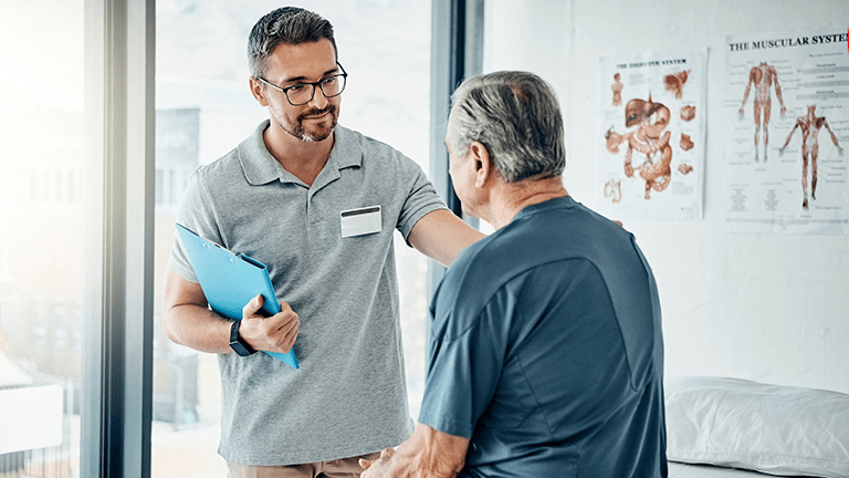 A caring physical therapist consulting with his mature patient in the rehabilitation center