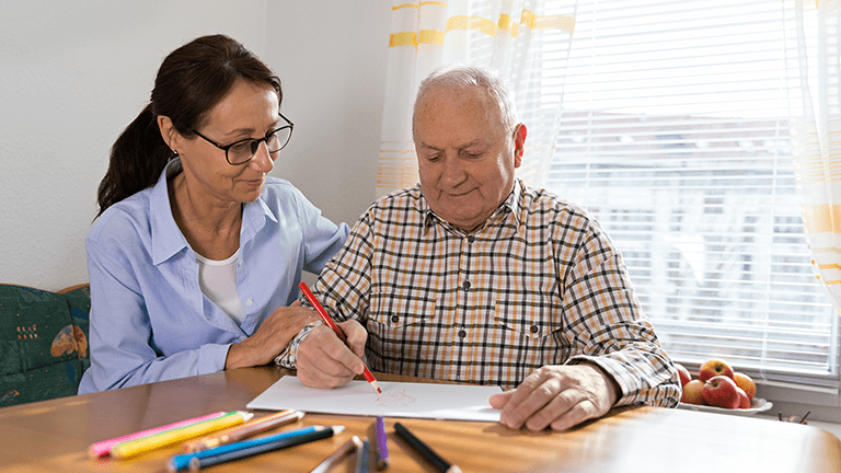 Occupational Therapsit works with senior adult man on fine motor skills.