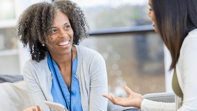 Encouraging female counselor gestures as she talks with a female client.