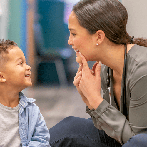 A speech therapist teaches a young boy how to sound out words.