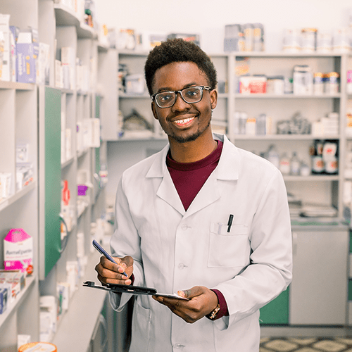 Male Pharmacist smiles at camera while holding clipboard.